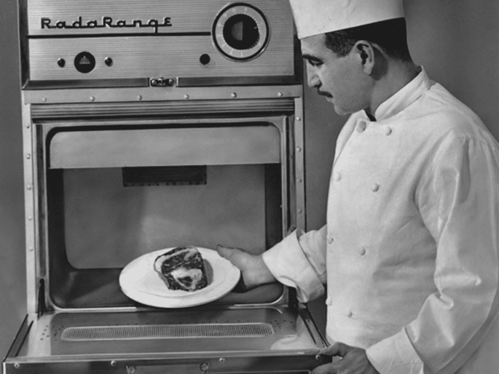 image of an early RadaRange microwave oven shown with chef holding a steak