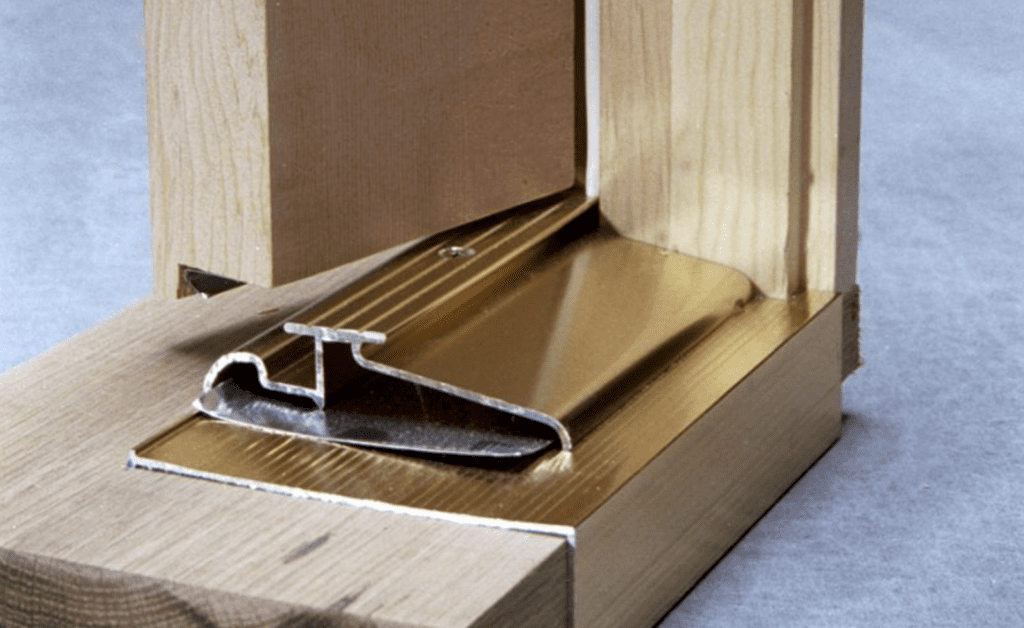 Metal interlock weatherstripping system at door threshold cutaway Image of brass door threshold